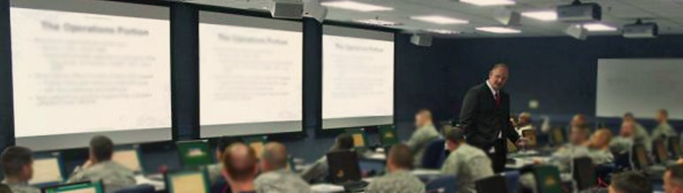 A man lectures in a large conference room.